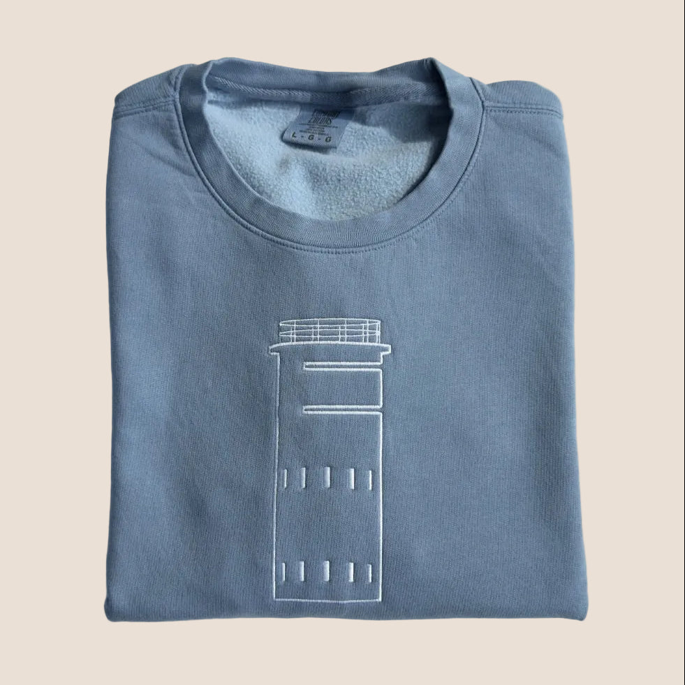 Folded blue sweatshirt with a white graphic on a white surface