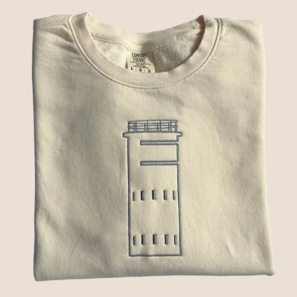 Folded beige sweatshirt with a graphic design on a white surface